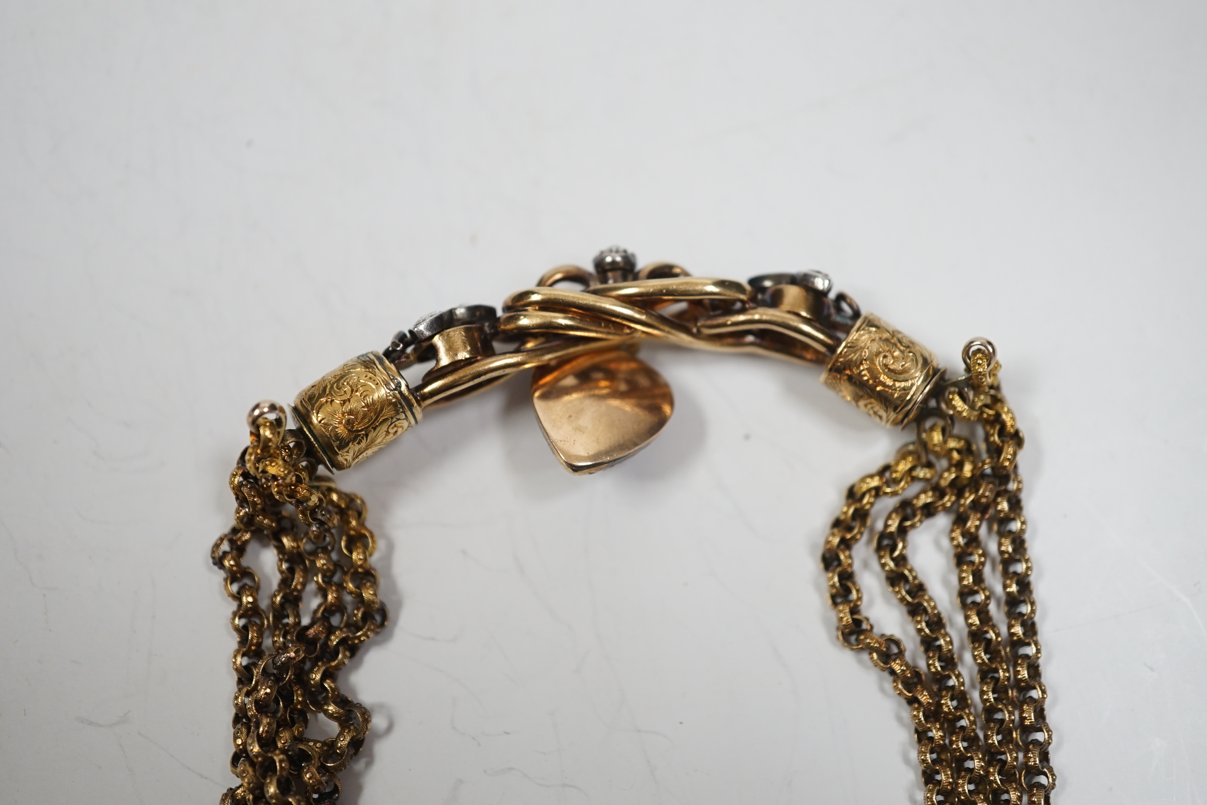 An antique yellow metal (test as 18ct) and rose cut diamond set triple strand bracelet, the central scrolling motif, hung with diamond set heart shaped charm, approx. 17cm, gross weight 30 grams.